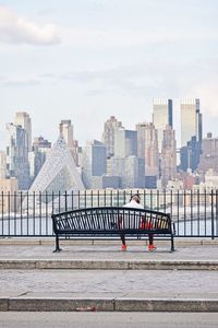 Rear view of man sitting on bench in city