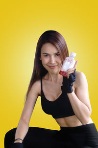 Portrait of a smiling young woman against yellow background