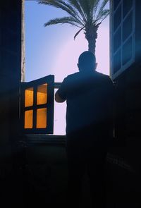 Low angle view of silhouette woman standing against house at night