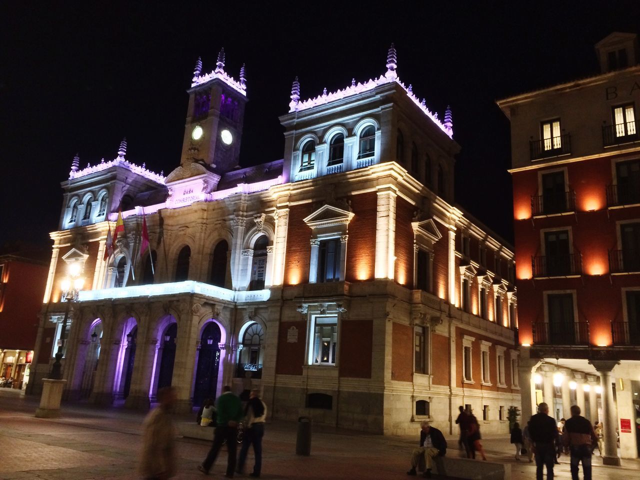 building exterior, architecture, night, built structure, illuminated, city, large group of people, men, person, street, city life, facade, walking, street light, sky, lifestyles, travel destinations, outdoors, lighting equipment