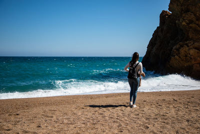 Full length of man standing on beach against clear sky