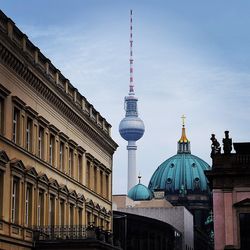 Low angle view of fernsehturm and buildings against sky