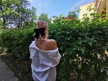 Portrait of young woman standing against plants