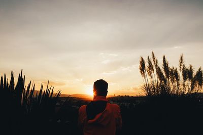 Rear view of woman against sky during sunset