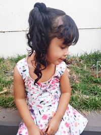 Girl looking down while sitting against wall