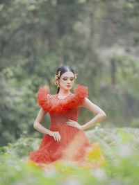 Portrait of young woman standing against trees