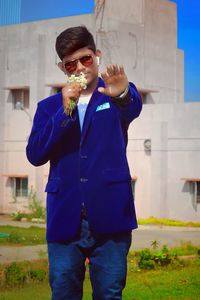 Young man wearing sunglasses standing against built structure