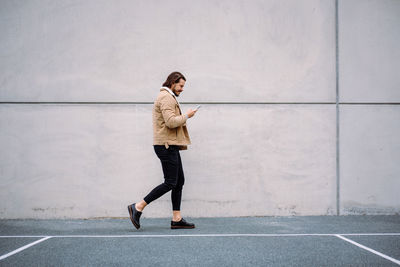 Side view of active businessman feeling busy and chatting messaging at the smartphone while walking