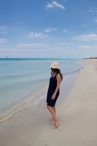 Full length of woman standing on shore against sky at beach