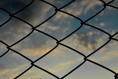 Full frame shot of chainlink fence against sky during sunset