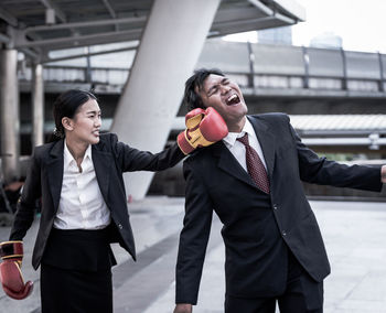 Businesswoman punching businessman while standing outdoors