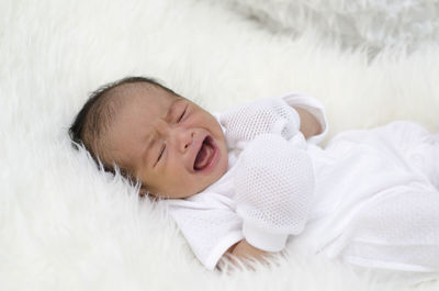 High angle view of cute baby boy crying on bed