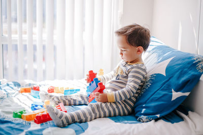 Cute baby toddler playing building with learning toy stacking blocks at home. early age education. 