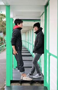 Side view of teenage boys leaning on wood