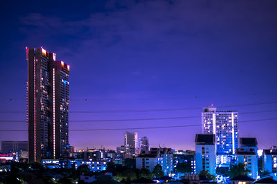 Illuminated buildings in city against sky at night