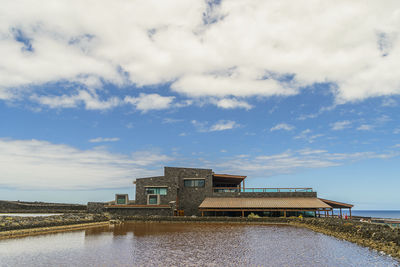 Building by lake against sky