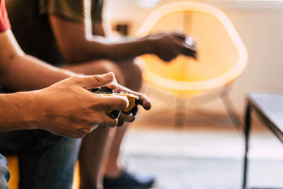 Close-up of friends playing video game at home