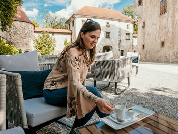 Portrait of happy young woman inside a castle courtyard. woman having a cup of coffee.