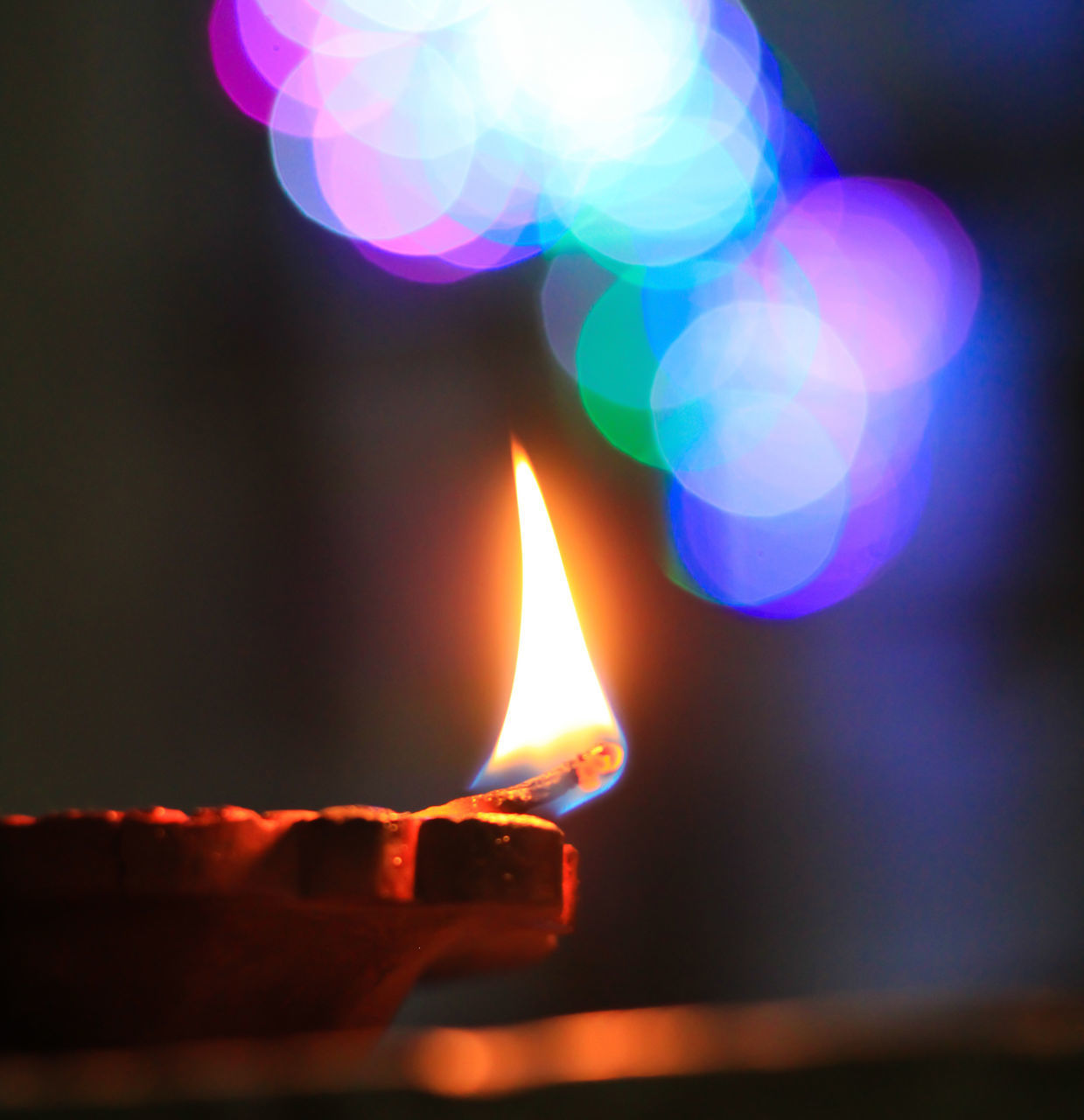 CLOSE-UP OF LIT CANDLE IN THE DARK