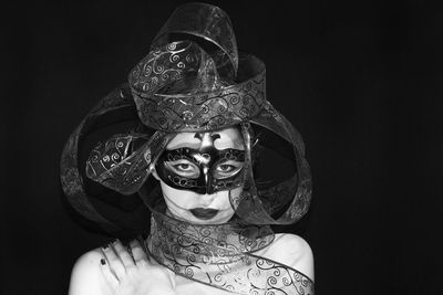 Portrait of woman wearing mask against black background