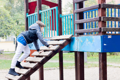 Little oy with protective face mask enjoying while playing in the park during covid-19 pandemic.