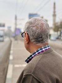 Side view of senior man standing on road against sky