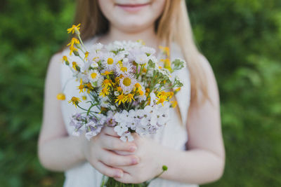 Midsection of girl holding flowers