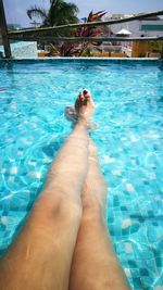 Low section of woman relaxing in swimming pool