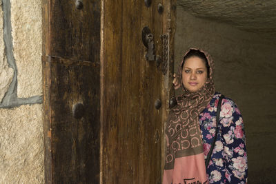 Portrait of woman wearing headscarf standing at doorway