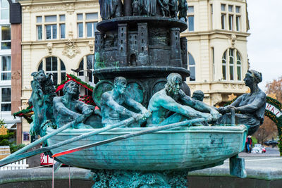 Statue by fountain in city