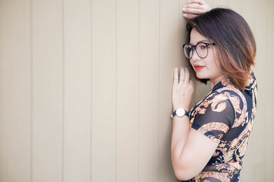 Young woman standing against wall