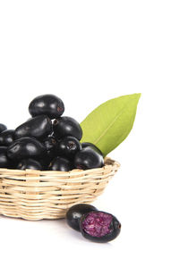 Close-up of black fruits in basket on white background