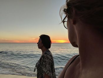 Female friends on shore at beach during sunset