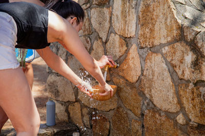 Woman filling water in bowl from tap