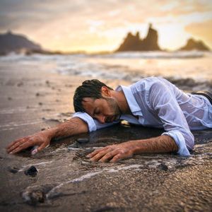 Exhausted man on beach after shipwreck