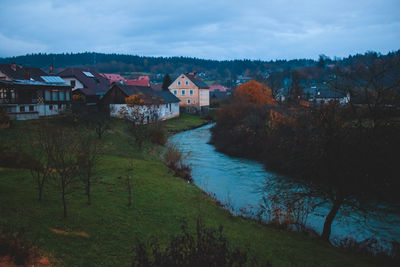 Houses by river against sky