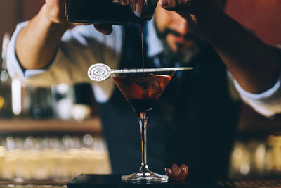 Midsection of mature bartender preparing cocktail in bar