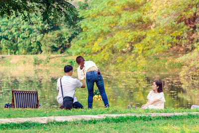 Rear view of people walking on grass against trees