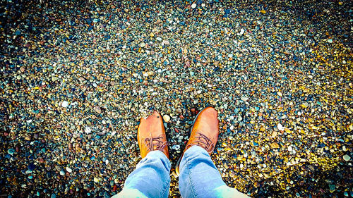 Low section of man standing on pebbles