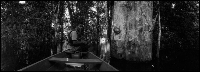 Woman standing by tree trunk in forest