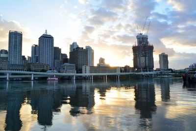 City at waterfront against cloudy sky