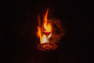 Close-up of burning candle against black background