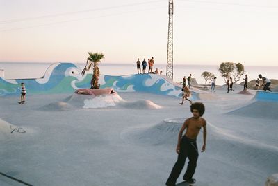People enjoying at beach against sky