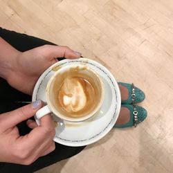 High angle view of woman holding coffee cup on table