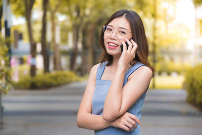 Portrait of smiling young woman using mobile phone in city