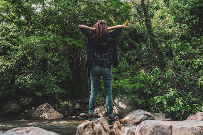 Rear view of person standing on rock in forest