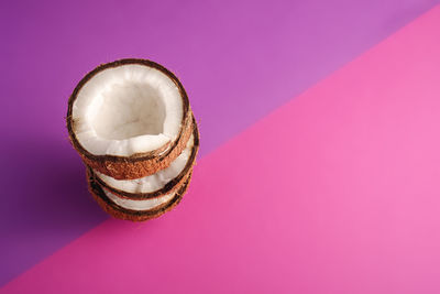 Stacked coconut fruits on violet and purple plain background, balance food tropical concept