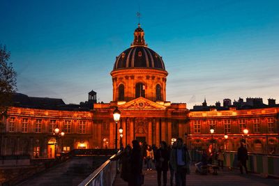 People at illuminated temple against sky at night