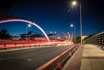 Light trails on road against sky at night