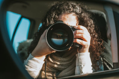 Close-up of woman photographing with camera in car